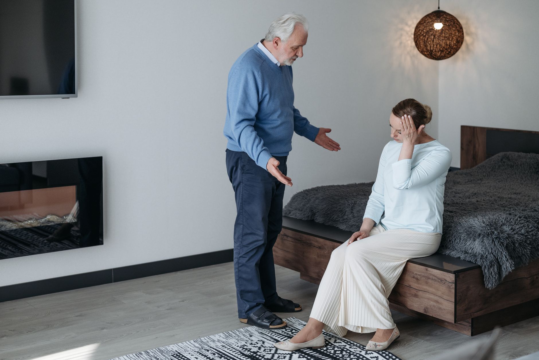 Elderly couple having a heartfelt conversation in a bedroom.