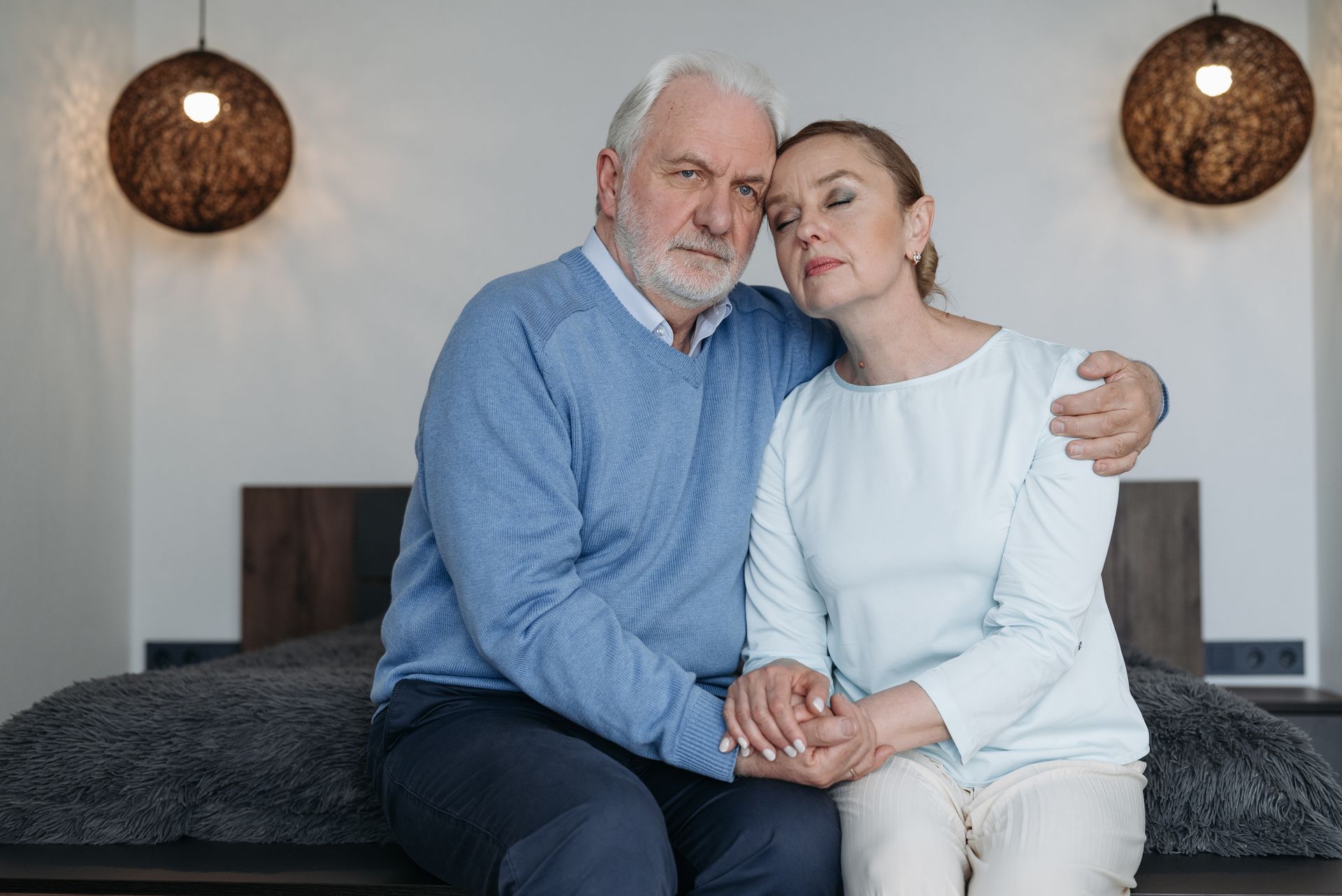 Senior couple sharing a comforting embrace, conveying love and support in a serene bedroom setting.