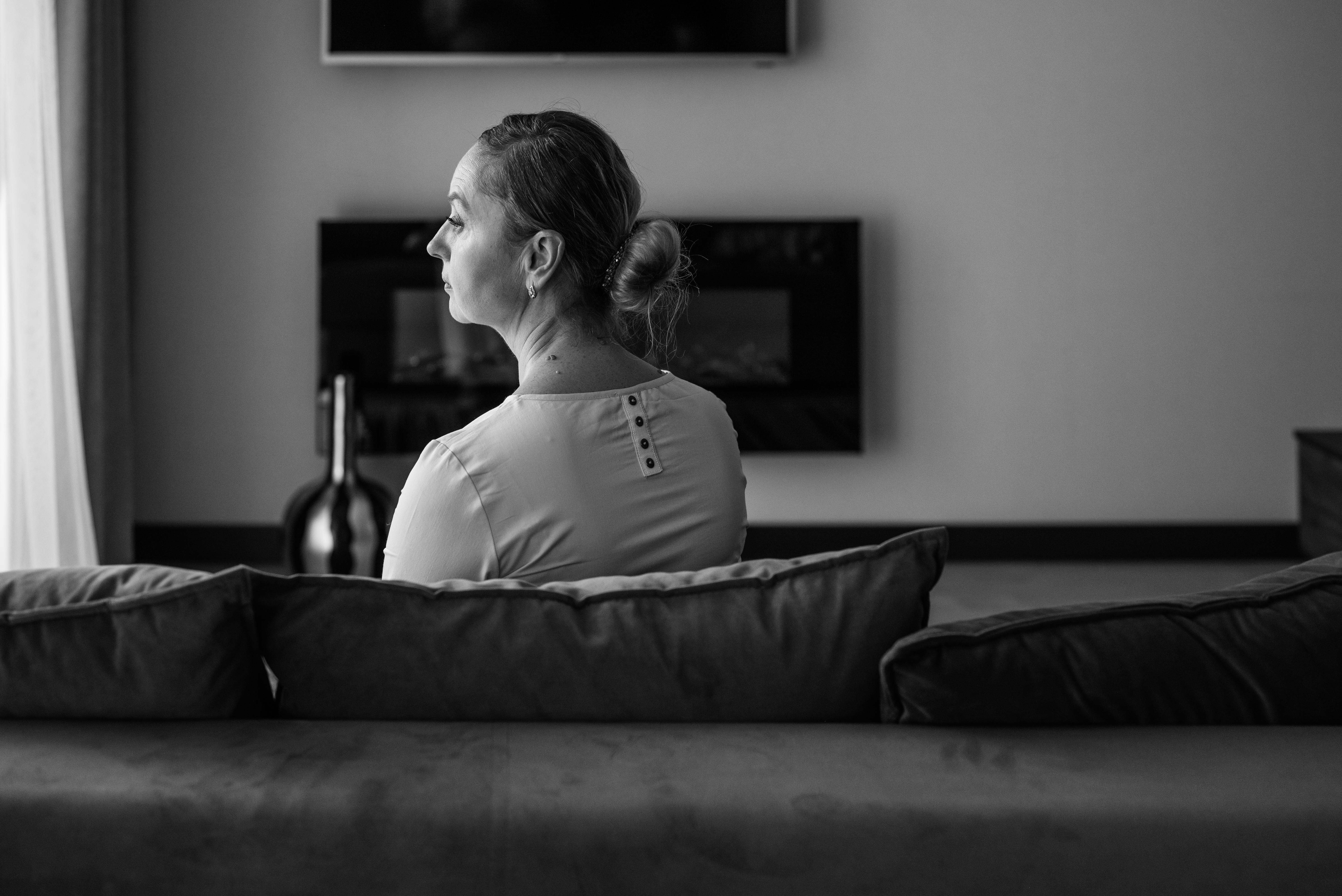 grayscale photo of a woman sitting on the couch alone