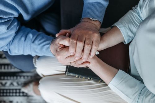 Free Close-up of two people holding hands, expressing comfort and empathy. Stock Photo