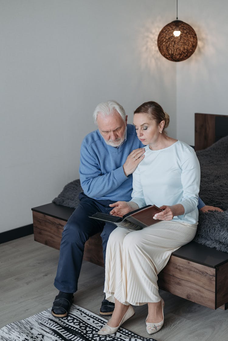 An Elderly Couple Looking At A Photo Album For Memories