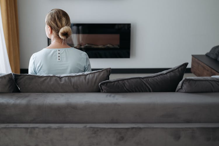 Back View Of A Woman Sitting On Gray Couch