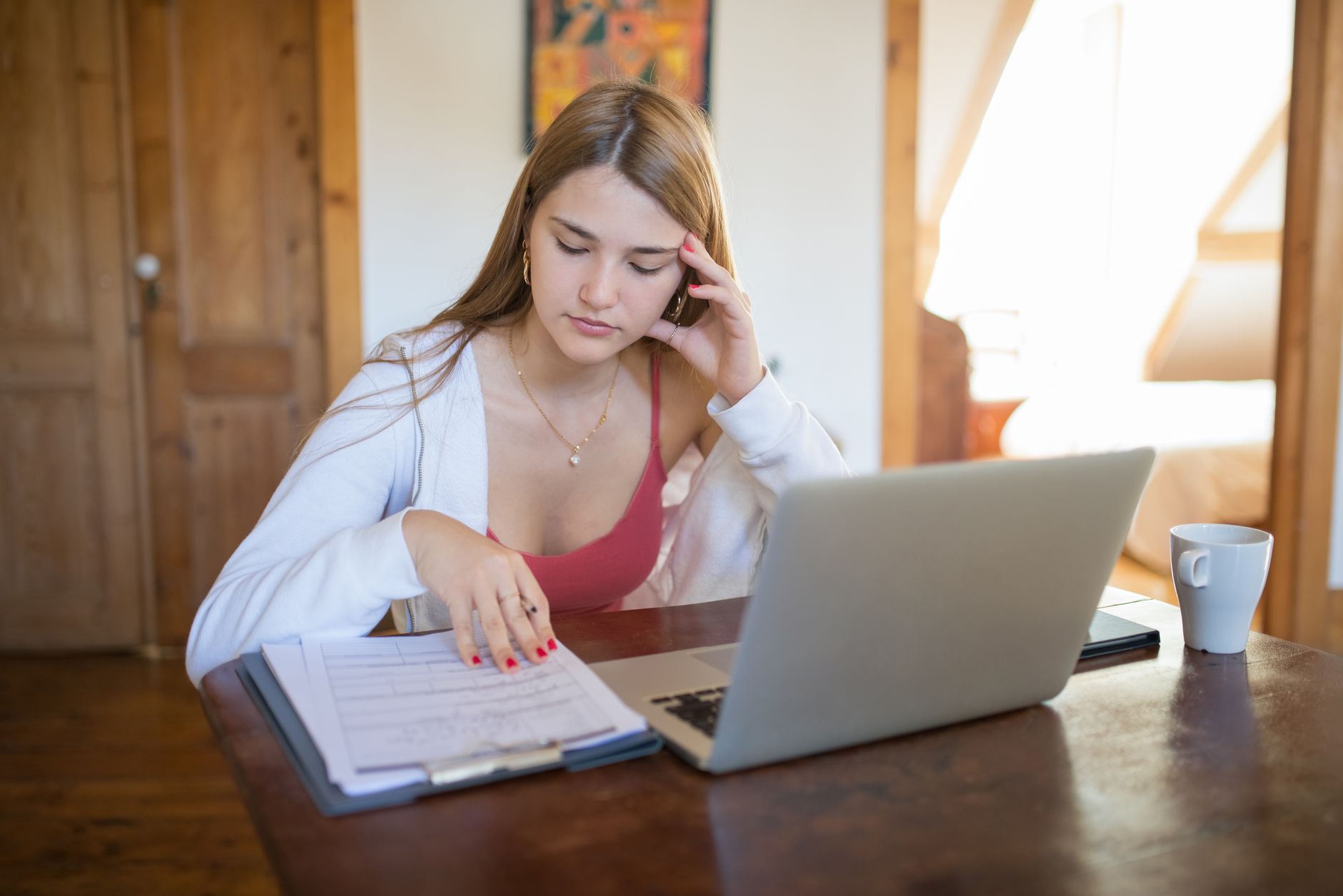Kvinde ved computer med dokumenter til registrering