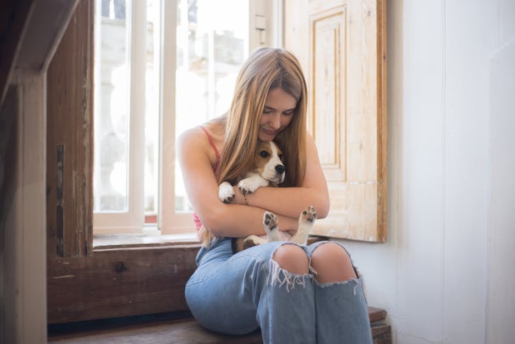 Woman Cuddling A Dog While Sitting