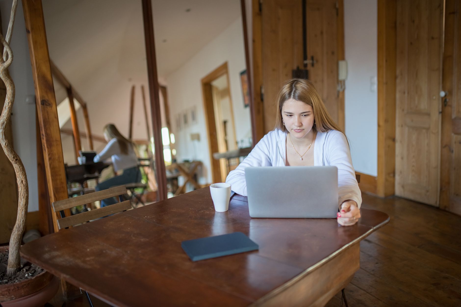 A person working at a laptop in a bright room with wooden shelving