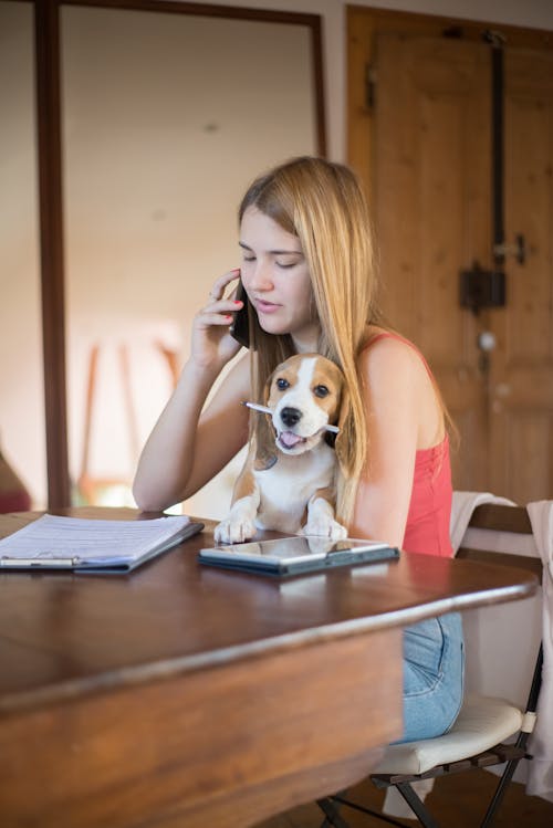 Woman Cuddling a Puppy While Using a Phone