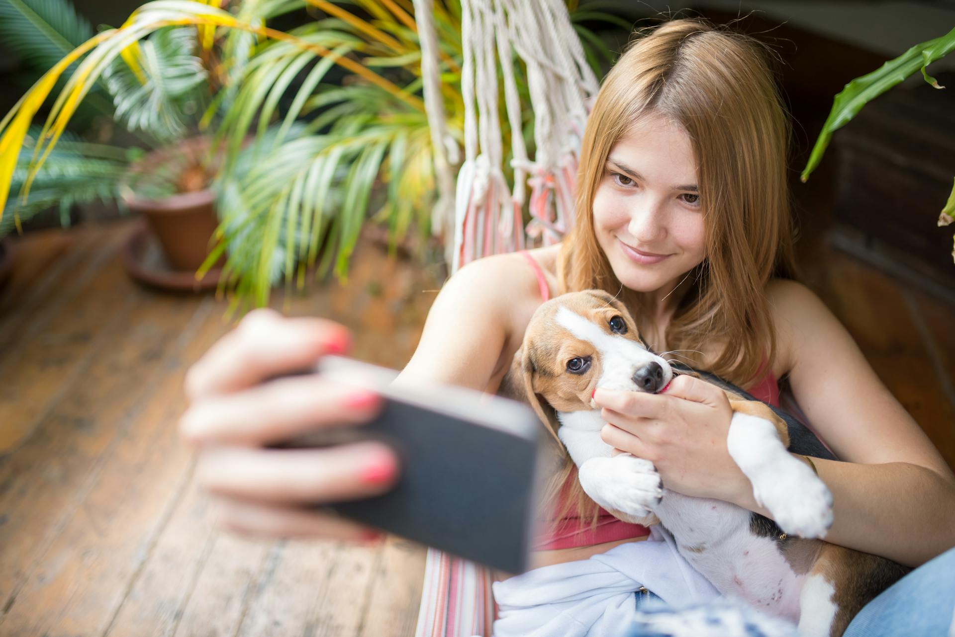 Kvinna i hängmatta tar en selfie med valp