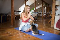 Woman in White Shirt and Blue Denim Jeans Sitting on Brown Wooden Floor With Brown Black