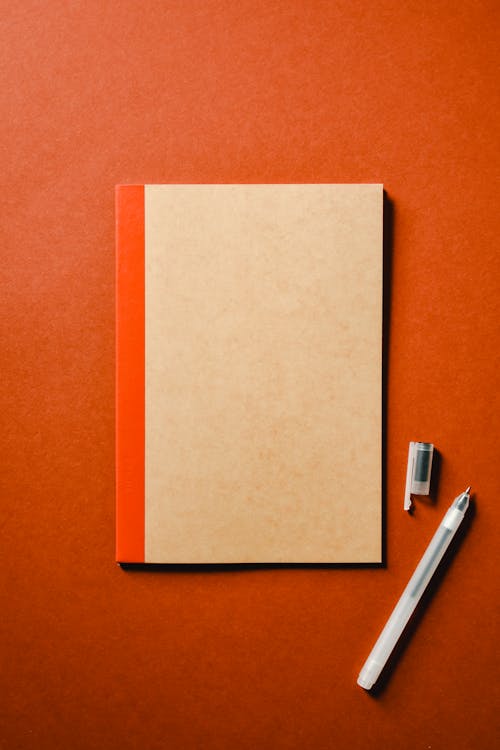 Notebook and Pen on Orange Surface