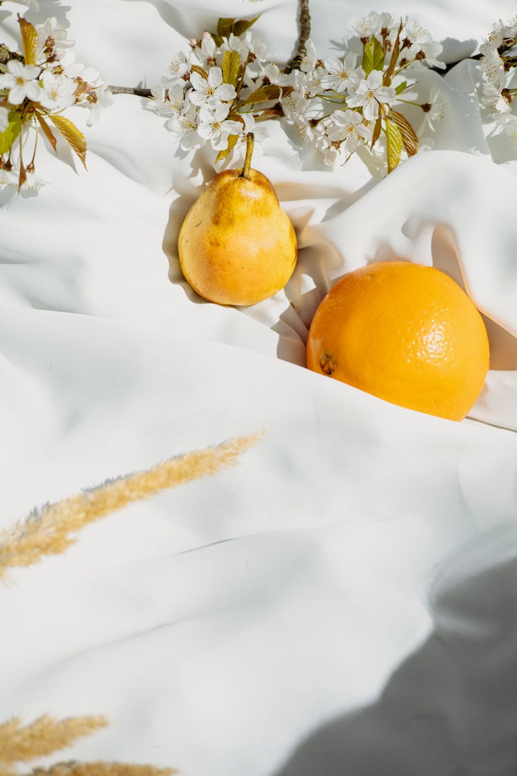 Pear And Orange Fruit On White Fabric