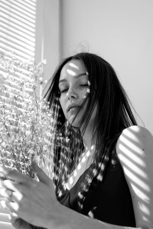 Free Artistic black and white portrait of a woman with shadows and flowers. Stock Photo