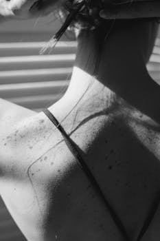 Black and white close-up of a woman's back with freckles and moles in vertical shot.