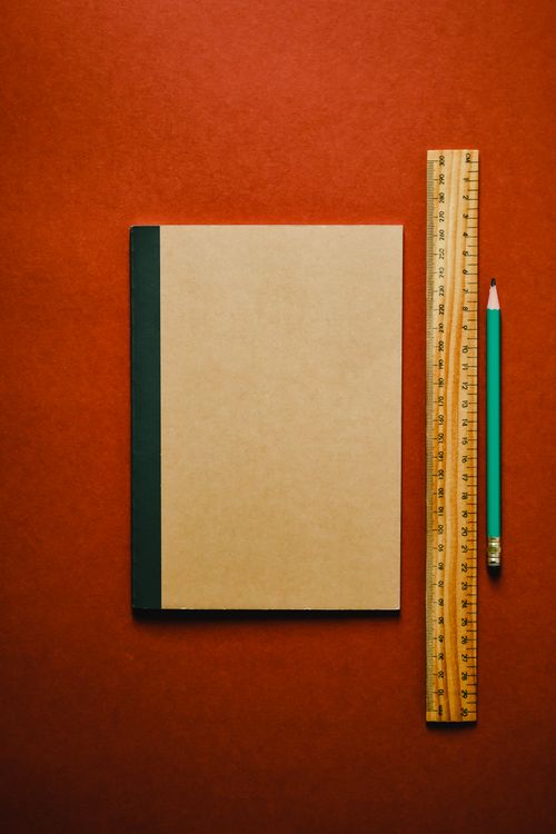 Free Flat lay of a notebook, pencil, and ruler on a red surface. Perfect for office-themed designs. Stock Photo
