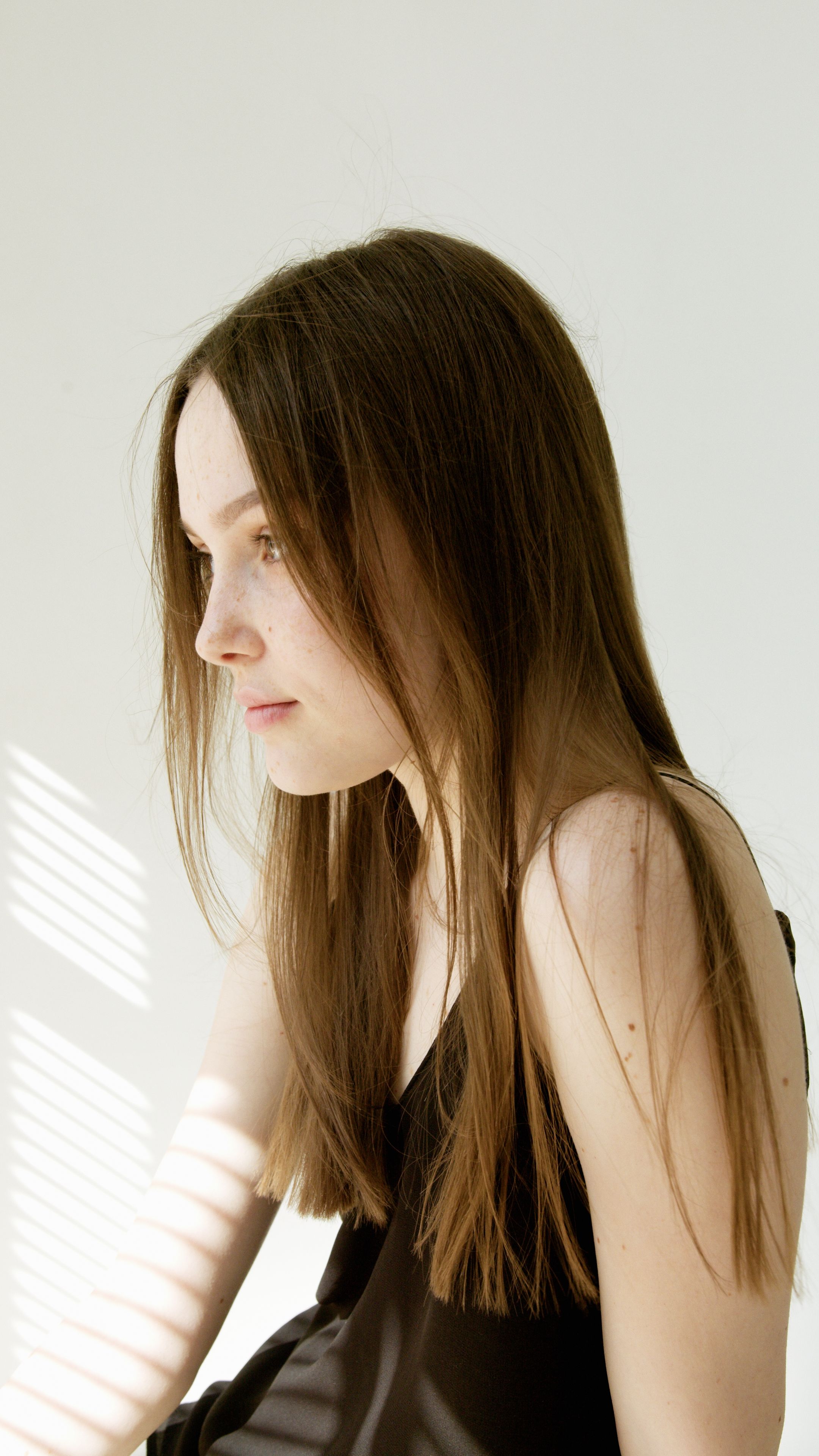 Elegant side view portrait of young woman in soft ambient light indoors.