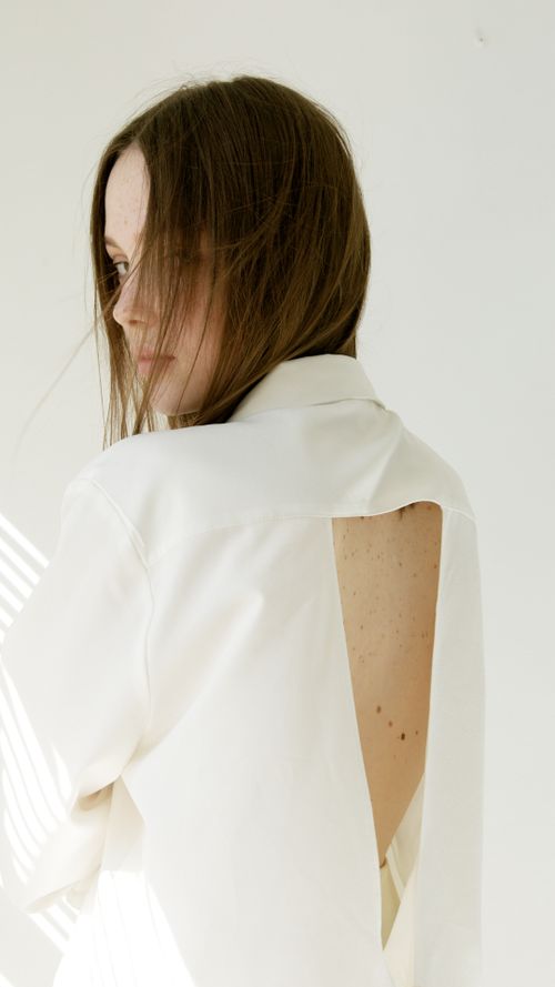 Free Portrait of a young woman in a backless white blouse with natural lighting indoors. Stock Photo