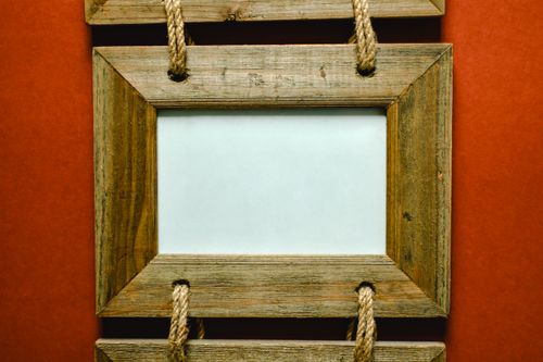 Free A rustic wooden photo frame with rope detail against a red background, perfect for decor themes. Stock Photo
