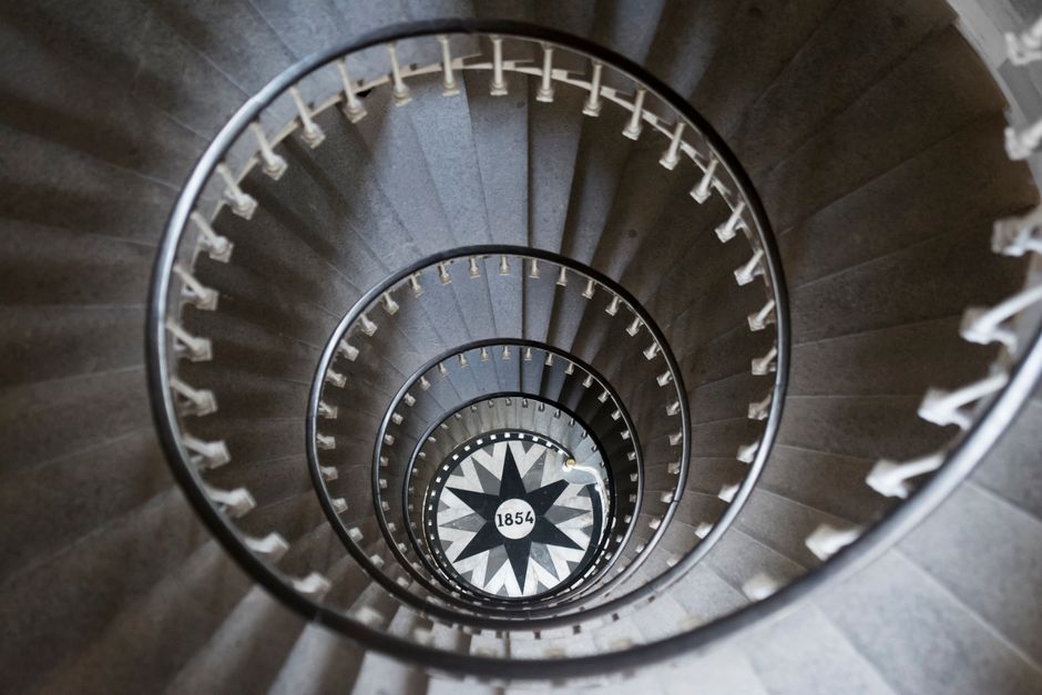 Captivating spiral staircase featuring a geometric design and 1854 date marker, viewed from above.