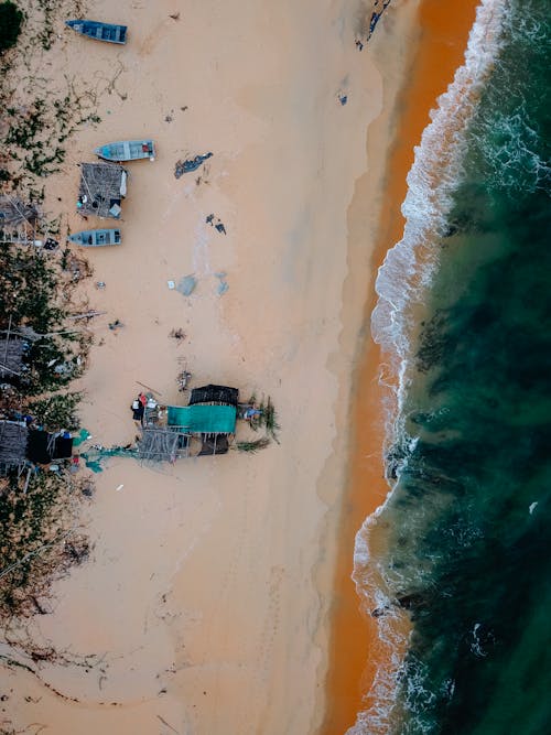 Boats moored on sandy beach near azure sea