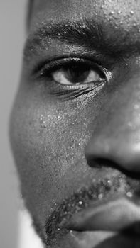 Intense monochrome close-up of man's face with detailed texture and perspiration.