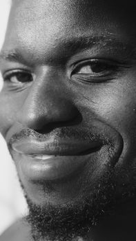Grayscale close-up portrait of a smiling man with a goatee, focusing on facial features and expression.
