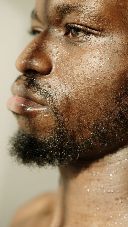 Free Intimate close-up of a bearded man with water droplets on his face, conveying a fresh and vibrant feeling. Stock Photo