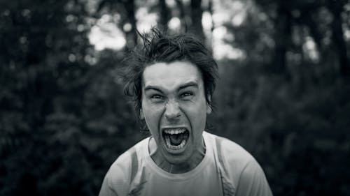 Black and White Photo of a Man Shouting while Looking at the Camera