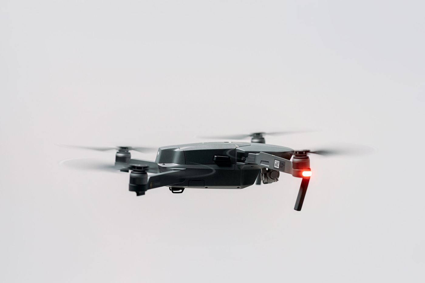 A compact folding camera drone hovering against a pale studio backdrop — photo by cottonbro studio on Pexels