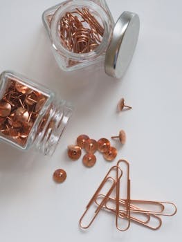 Copper pins and paperclips in glass jars for office organization.
