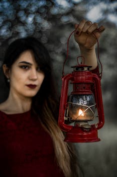 Mysterious woman holding a vintage red lantern, illuminating the night with a warm glow.