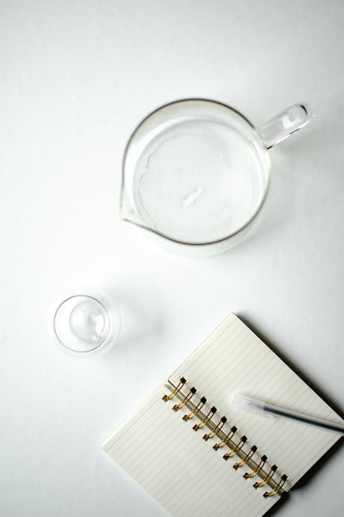 Clear Glass Items Beside White Notebook