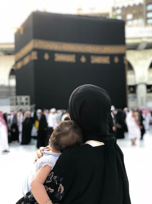 A Woman in Black Hijab Carrying a Baby
