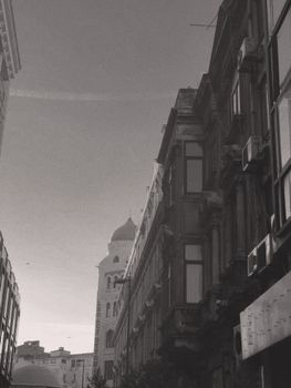 Moody black and white photo of city buildings and tower in vintage style.