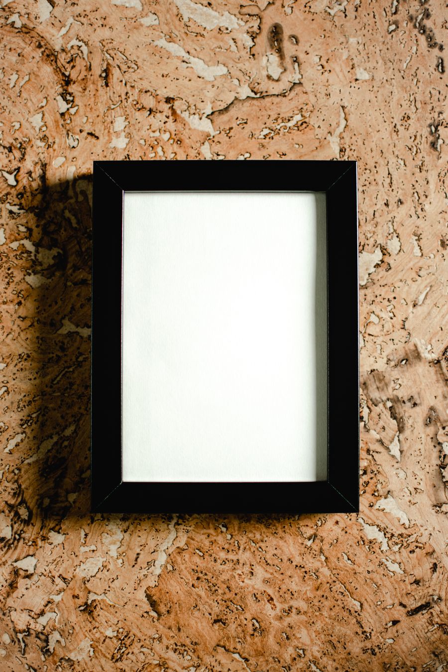 An empty black frame on a cork surface