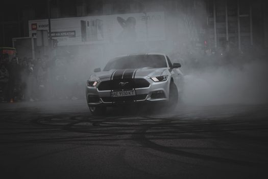 Powerful Mustang performing a thrilling drift amidst smoke, capturing high-energy street action.