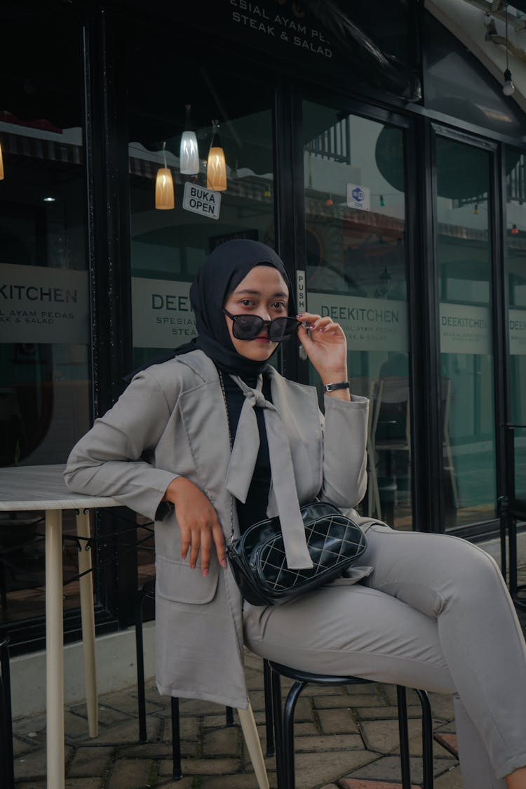 Woman In Gray Clothes Taking Off Her Sunglasses While Looking At The Camera