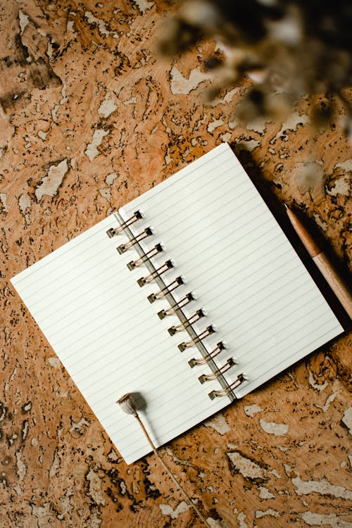 White Notebook on Brown Marble Table