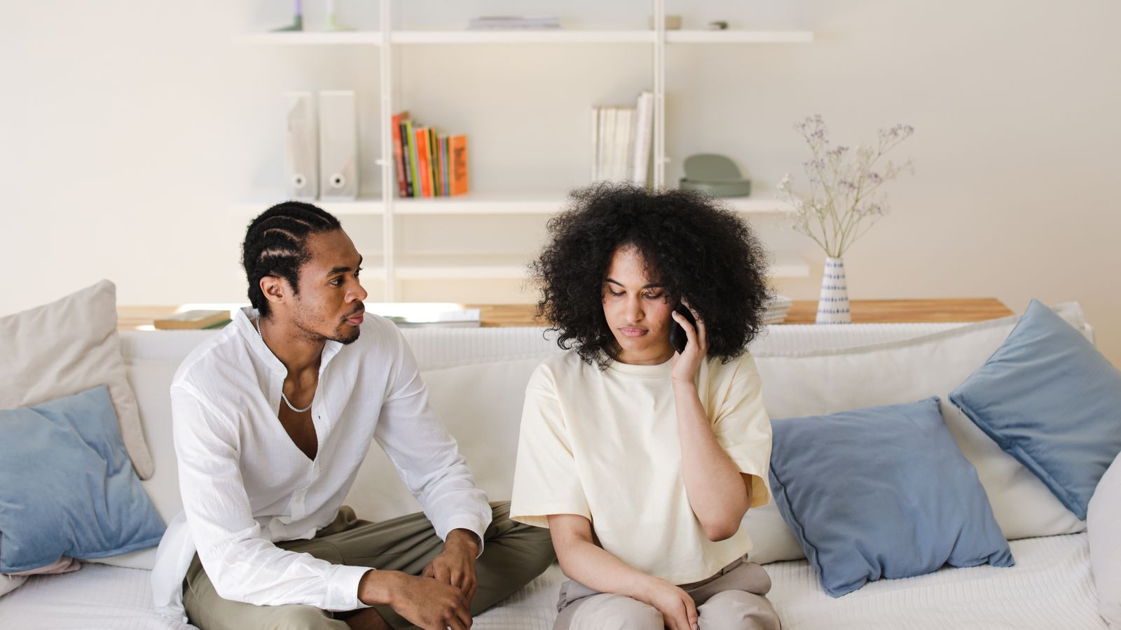 Two people seated on a sofa, one holding a phone