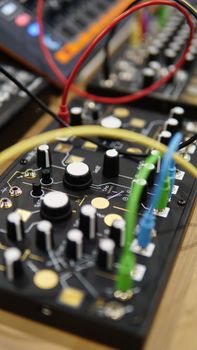Detailed view of an audio mixer with various knobs and vibrant wires connected.