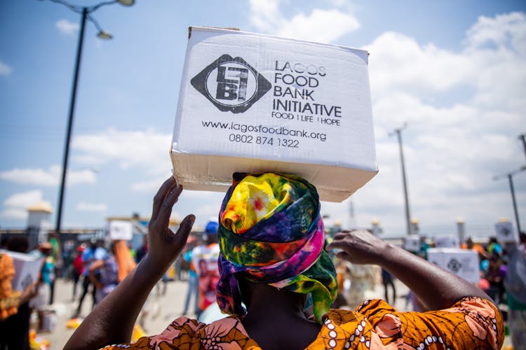 A Woman Carrying Box Using Her Head