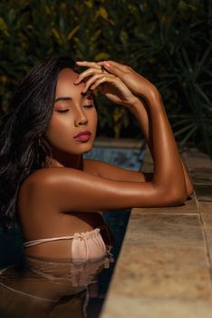 A serene moment of a woman with closed eyes enjoying a poolside setting under warm lighting.