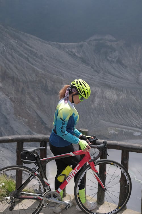 Photo of a Woman Standing Beside Her Red Road Bike