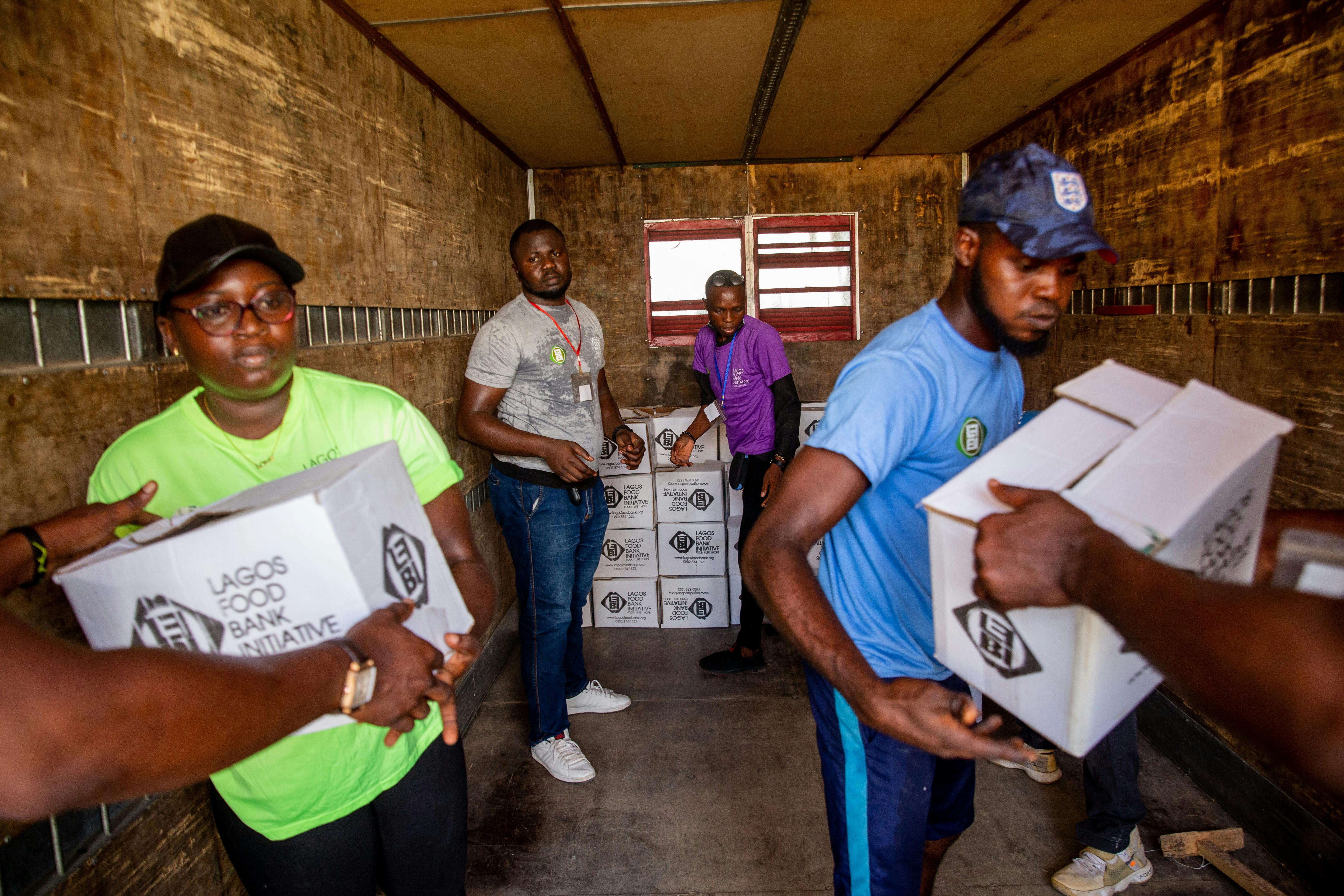 Free Dedicated volunteers organize food boxes in a truck for community distribution. Stock Photo