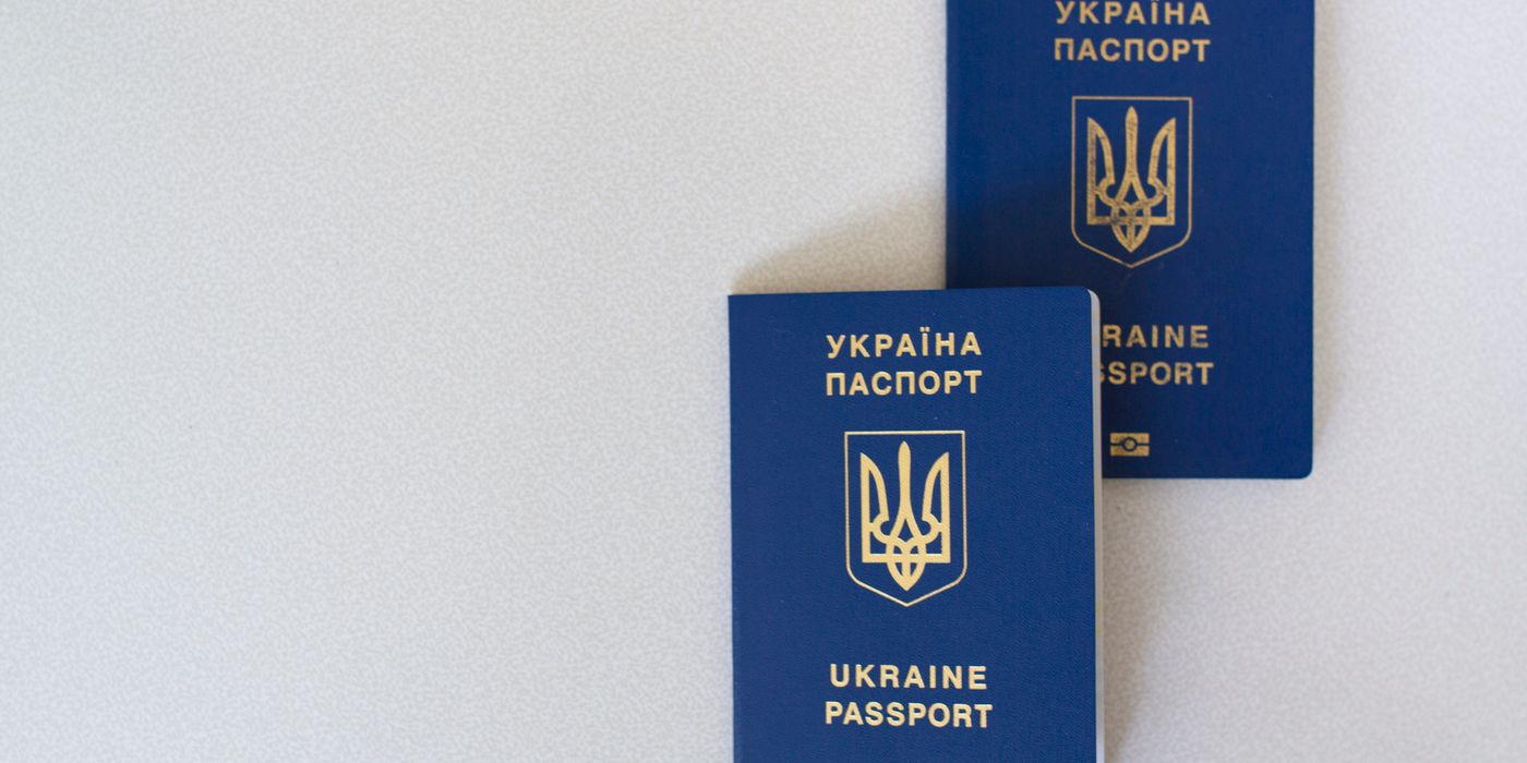 Two blue Ukrainian passports placed on a white surface, close-up view.