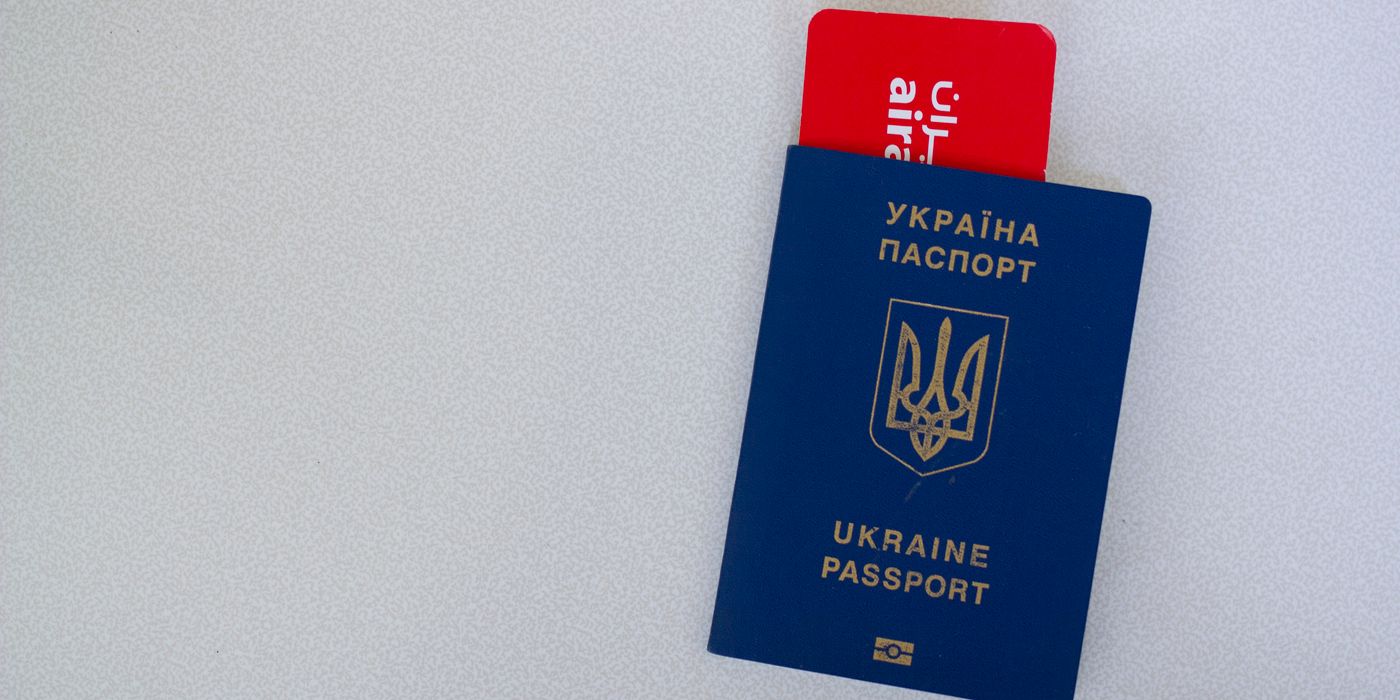 Close-up of a Ukrainian passport with an airline boarding pass on a white surface.