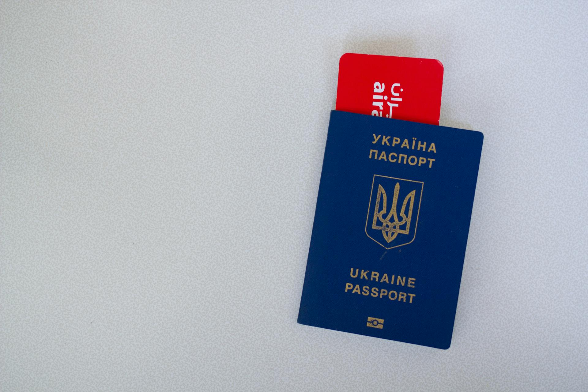 Close-up of a Ukrainian passport with an airline boarding pass on a white surface.