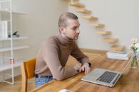 Man in Brown Sweater Sitting at the Table Using Macbook