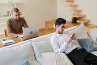 Man in White Long Sleeve Shirt Sitting on Bed Using Macbook