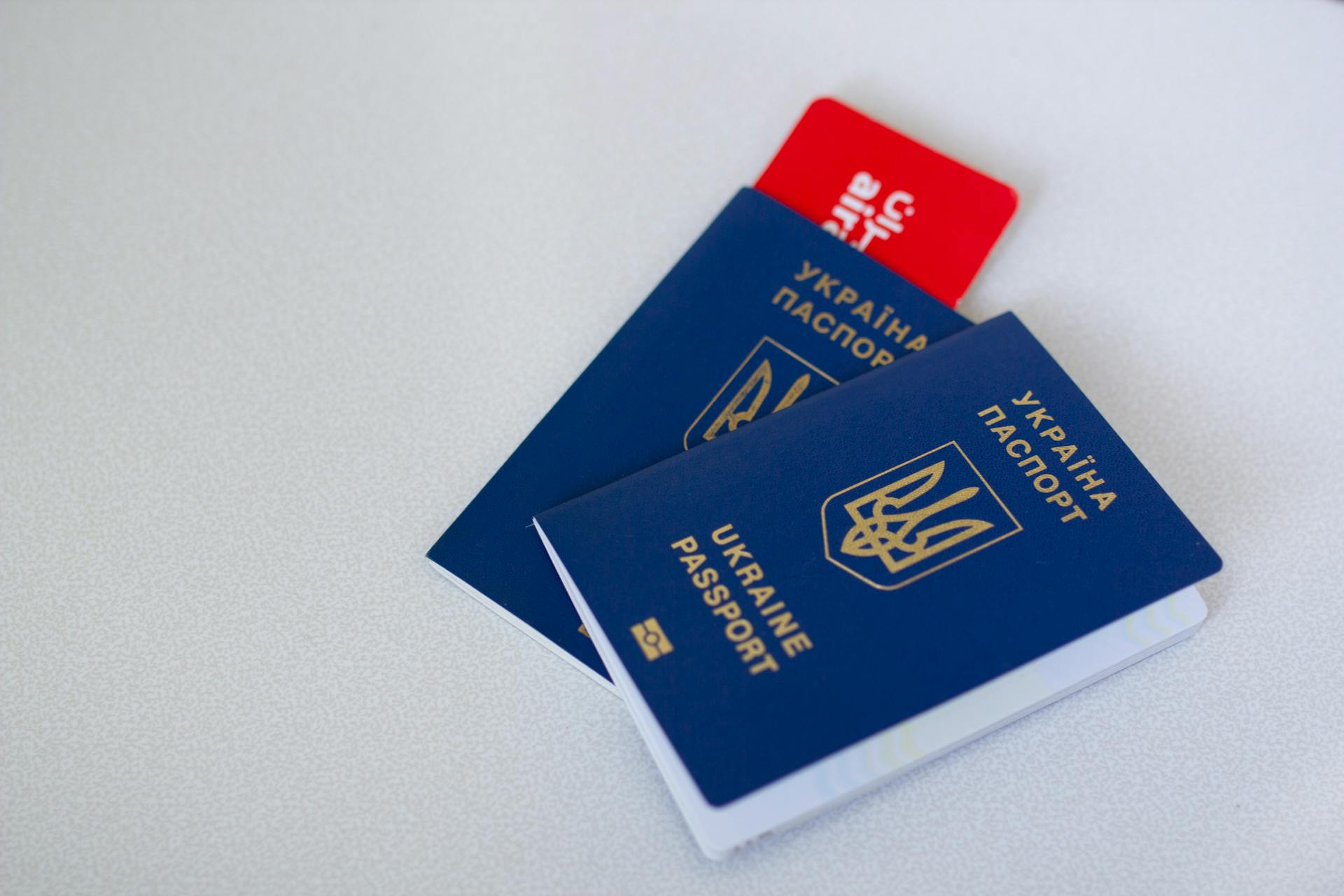 Close-up of Ukrainian passports and travel card on a light surface with ample copy space.