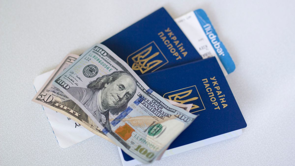 Close-up view of Ukrainian passports with US dollar bills, symbolizing travel readiness.