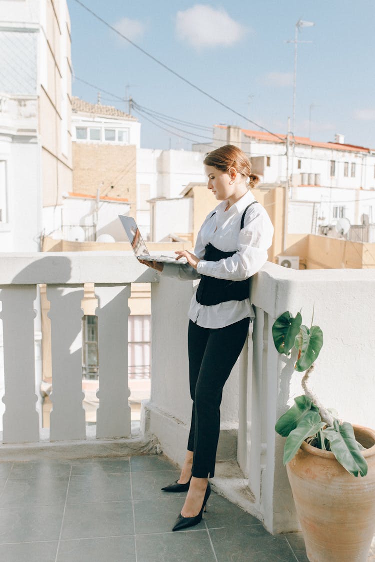 A Businesswoman Using A Laptop On A Balcony